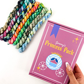 7 skeins of variegated yarn and a hand holding a pink box with Jimmy's Princess Pack text and an illustrated blue carriage on a white background