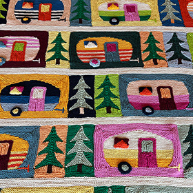 A close up shot of a knit blanket of campers and trees