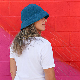 A model wearing a blue crocheted bucket hat