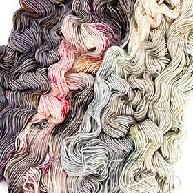 Pink, white, and grey skeins of yarn unraveled