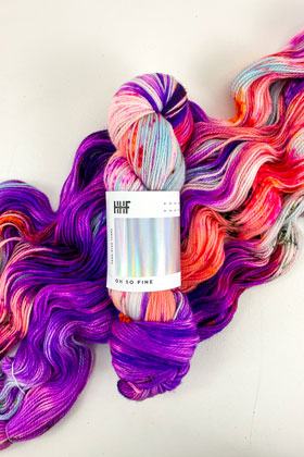 A skein of pink and purple variegated yarn laid over a unraveled skein of the same yarn