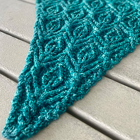 an in progess shot of a blue knit shawl