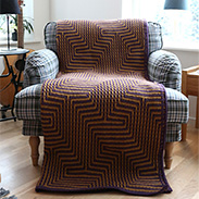A brown crocheted blanket drapped on a chair