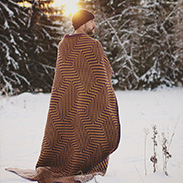 A model wearing a crocheted brown blanket