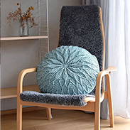 A crocheted daisy circle pillow on a chair