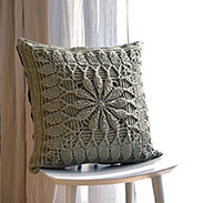 A crocheted daisy square pillow on a chair