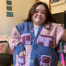 A model wearing a blue, pink, and purple crocheted cardigan