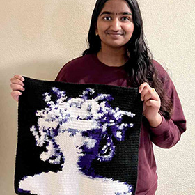A model holding a tapestry made to look like Medusa