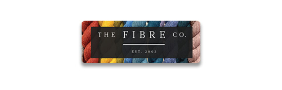 The Fibre. Co Est. 2003 text over a black box on top of colorful skeins of yarn