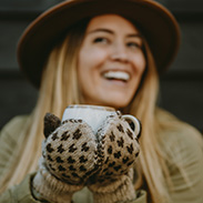 A model wearing knit gloves and holding a coffee cup