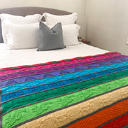 A rainbow gradient blanket draped over a bed