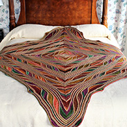 A colorful and diamond shaped blanket draped over a bed