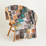 A granny square blanket draped over a chair