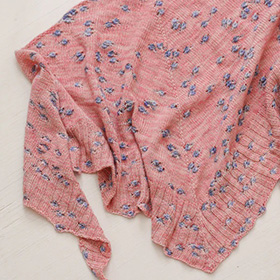 A pink knit shawl with blue baubles