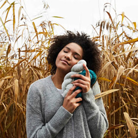 Rosy Green Wool yarn being held by a woman in a field
