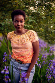 A model wearing a pink and orange knit top in a field of flowers