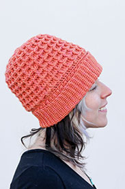 A model wearing a pink crocheted beanie