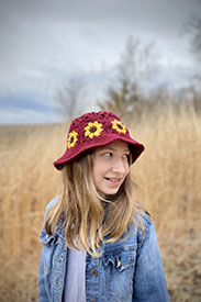A model wearing a red and yellow crocheted flower bucket hat