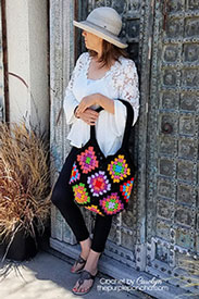 A model holdinig a bright and colorful granny square crocheted bag