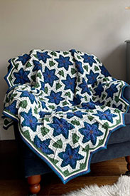 A blue flower granny square crochet blanket laying on a blue chair
